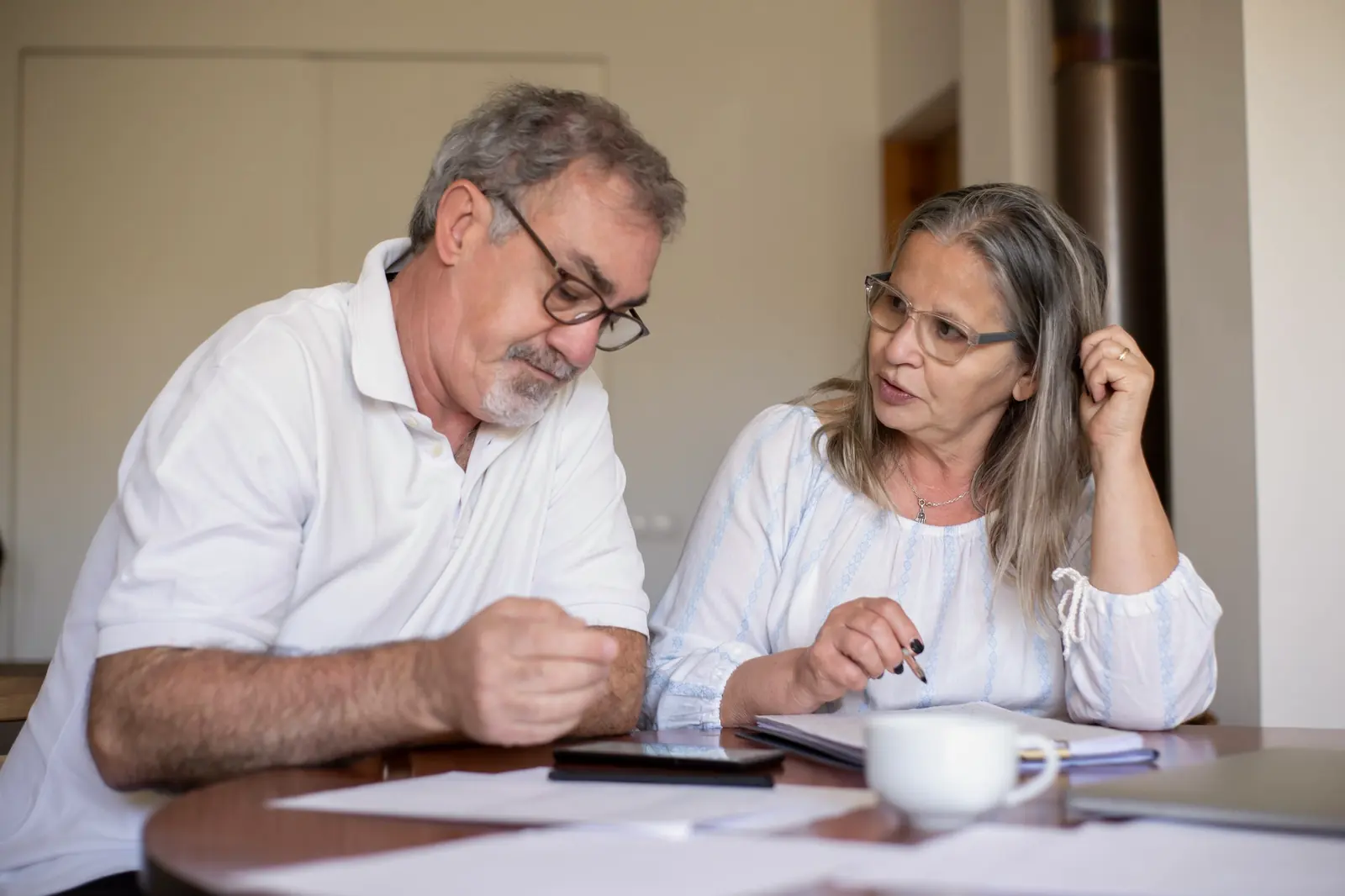 Casal sentado à mesa da cozinha conversando sobre documentos